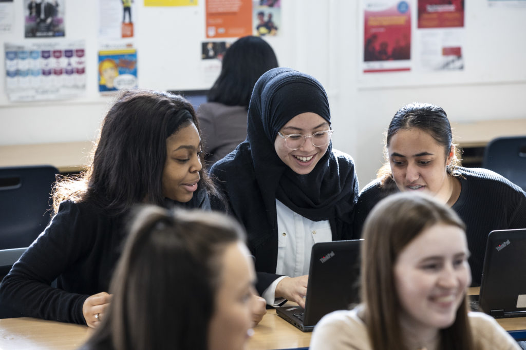Post-16 students talking to one another around a laptop