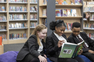Three students sat on bean bag chairs reading
