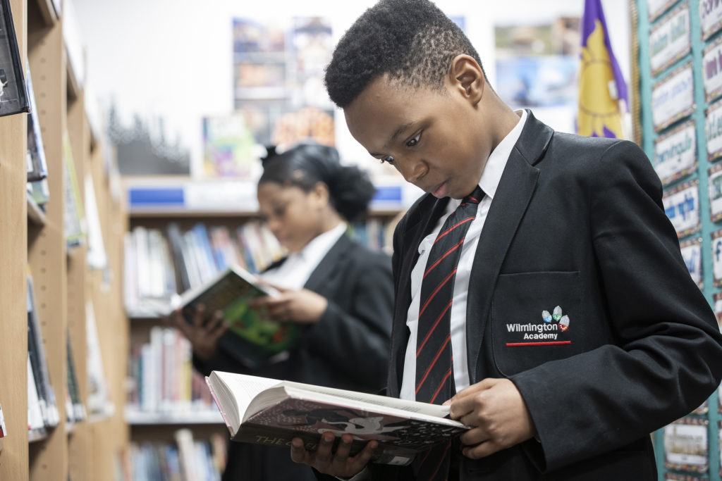 WA student reading a book with another student in the background