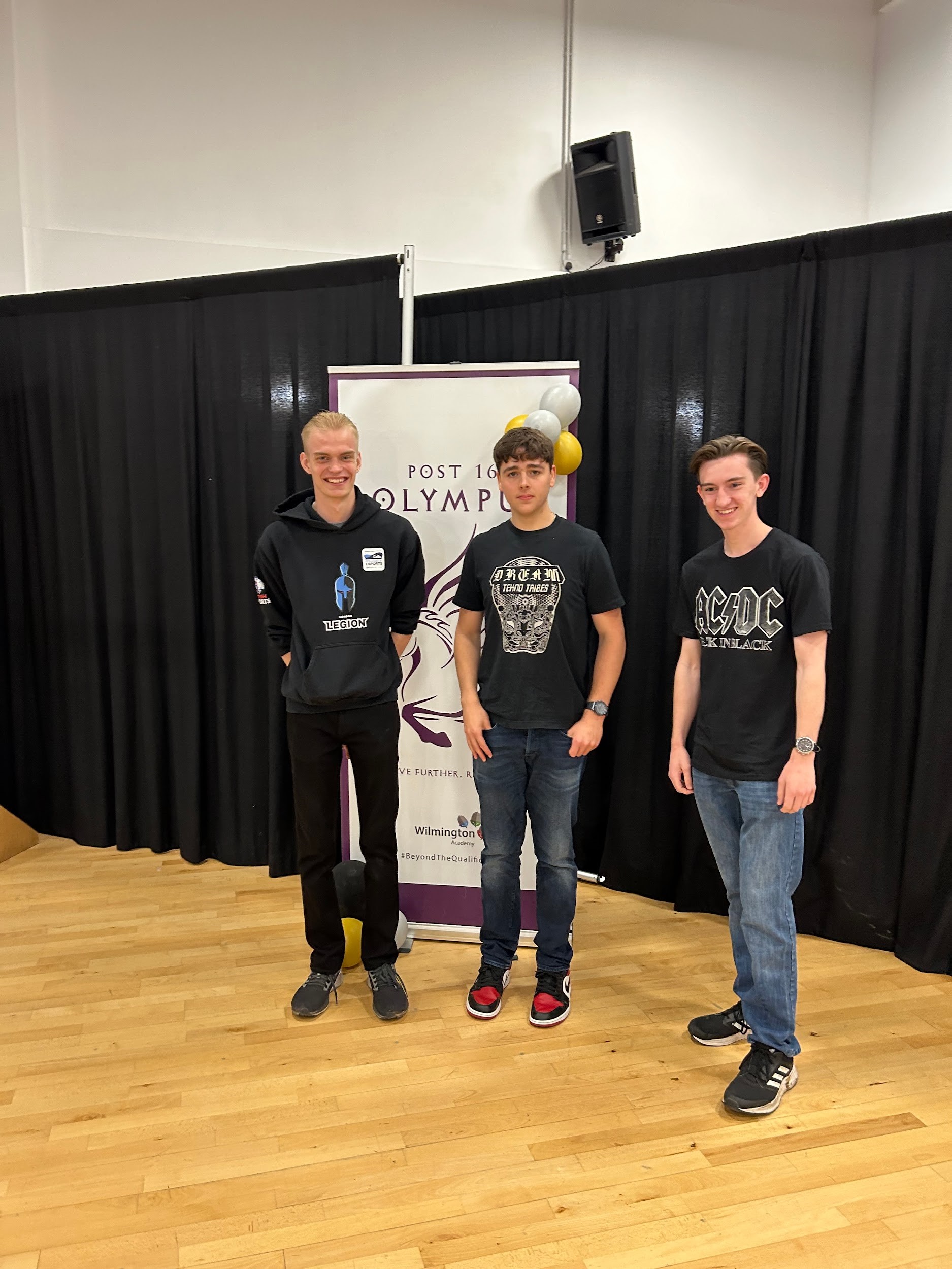 3 Wilmington students standing in front of IB Banner