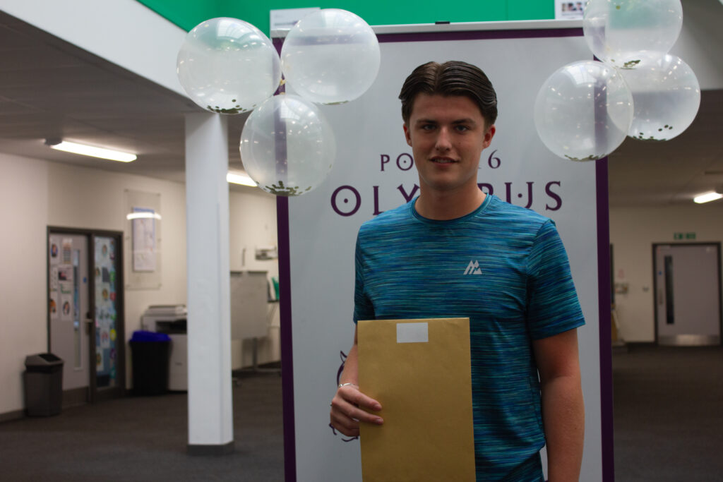 A male Post-16 student is pictured smiling for the camera, whilst holding his A-Level results in his hand.