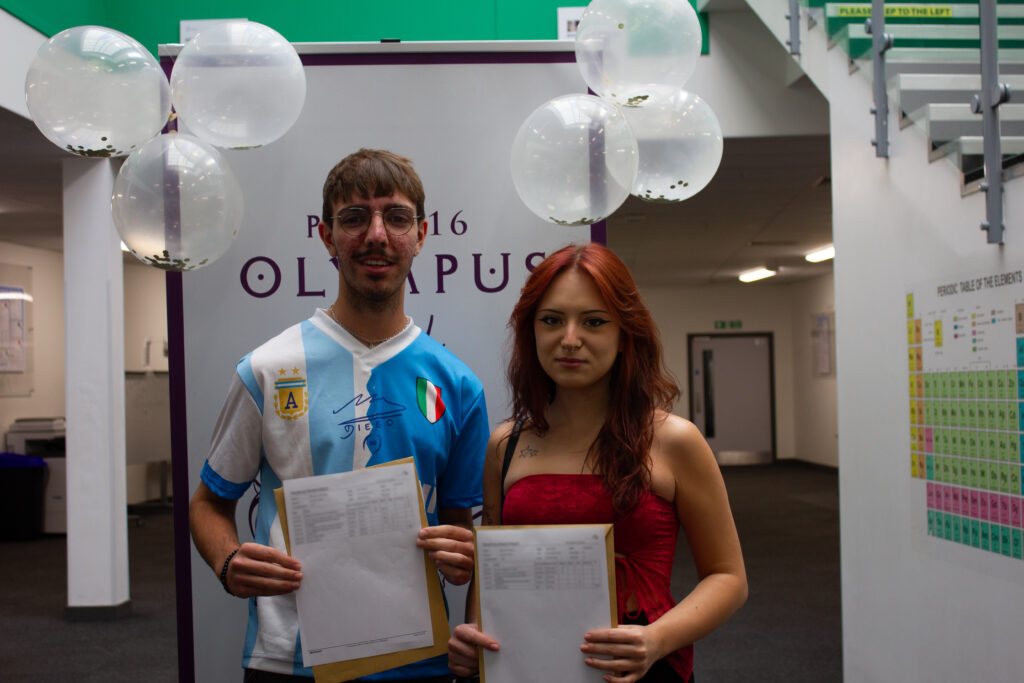 Two Post-16 students, one male and one female, are pictured smiling for the camera, whilst holding their A-Level results in their hands.